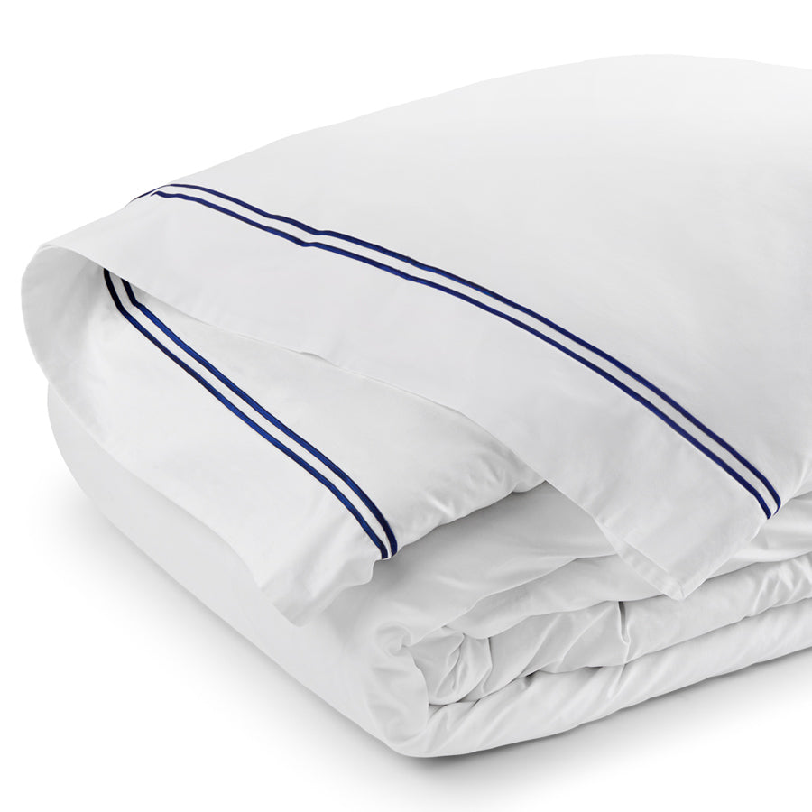 Close-up of folded white duvet cover with navy double satin-stitch border showing crisp cotton sateen finish.