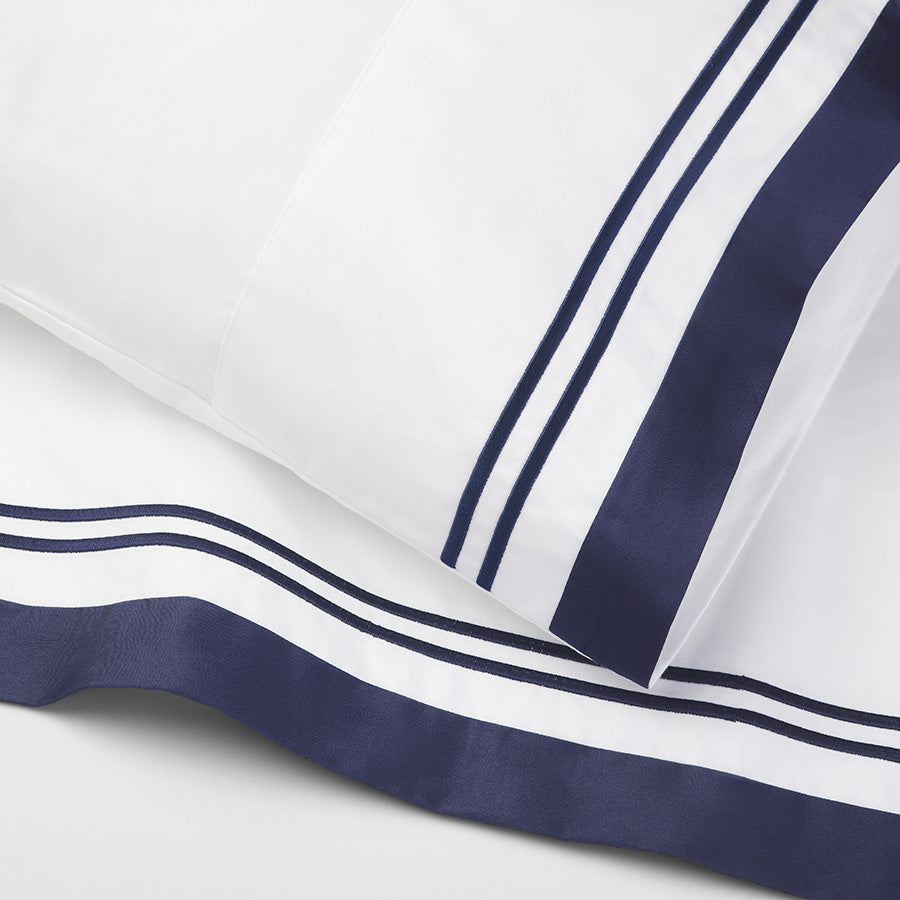Detailed view of Flaxfield Linen Manhattan Pillowcases and Sheet Set, showcasing crisp white 400TC cotton sateen, navy header, and satin-stitch embroidery.