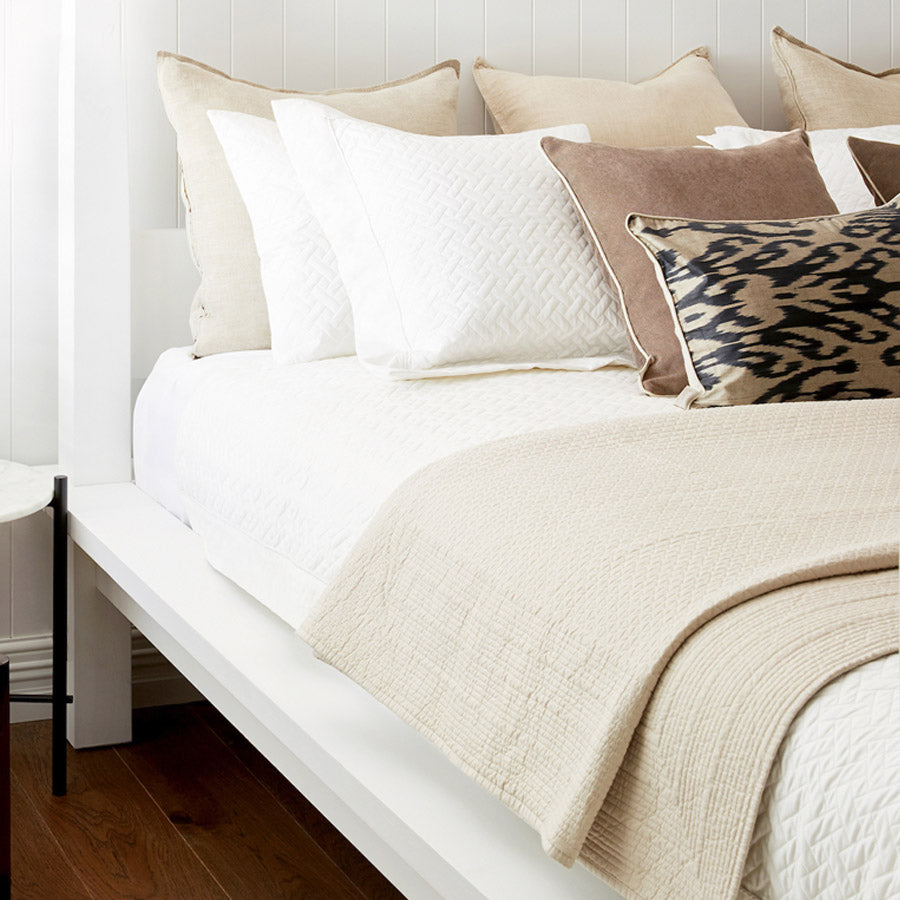 Bed displaying a quilted bedspread in a linen colour