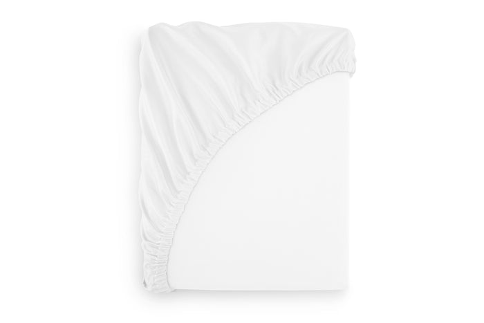 A white fitted sheet with French seams fitted on a mattress, presented in a folded state.