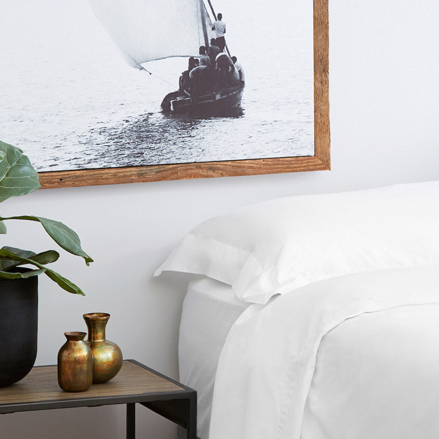 White cotton fitted sheet styled on a bed with flat sheet and pillowcases