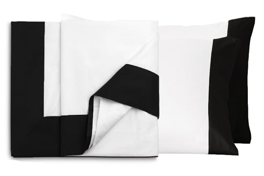 Folded Resort sheet set featuring white flat sheet with black European turnback and matching cuffed pillowcases