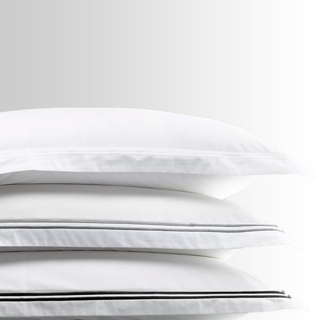 Stack of folded Classique King Pillowcases showing crisp cotton sateen fabric and black satin-stitch borders.