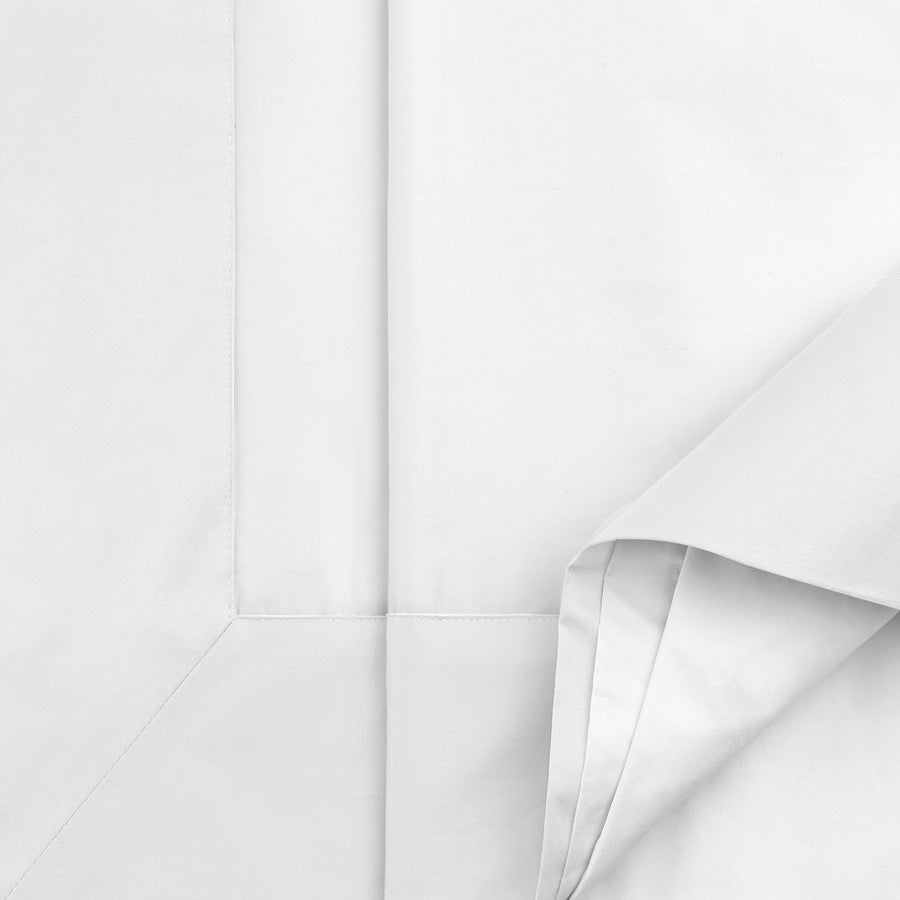 Close-up of white cotton sateen flat sheet showing mitred European turnback and smooth sateen finish